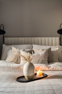 Cozy softly lit bedroom with a vase of flowers and candle creating a peaceful nighttime atmosphere
