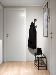 A hallway with a coat rack and a coat hanging on the wall
