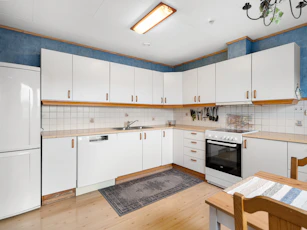 A kitchen with white cabinets and a wooden table
