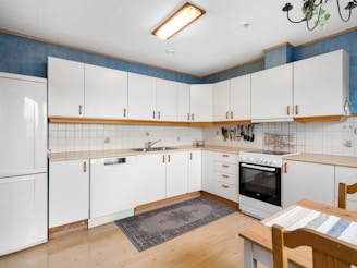 A kitchen with white cabinets and a wooden table