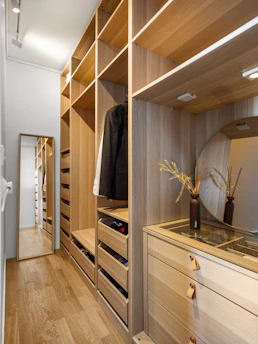 A walk in closet with a mirror and drawers