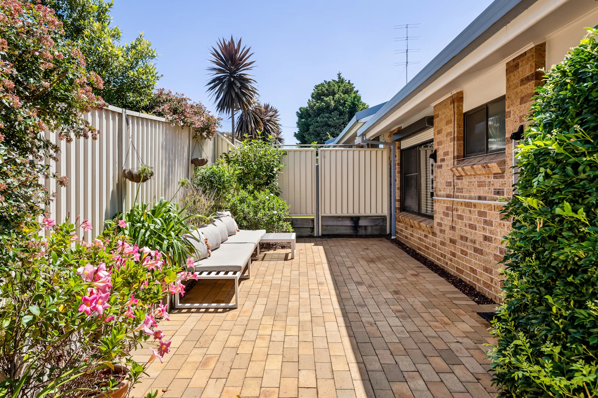 Backyard paver walkway and patio with surrounding garden plants