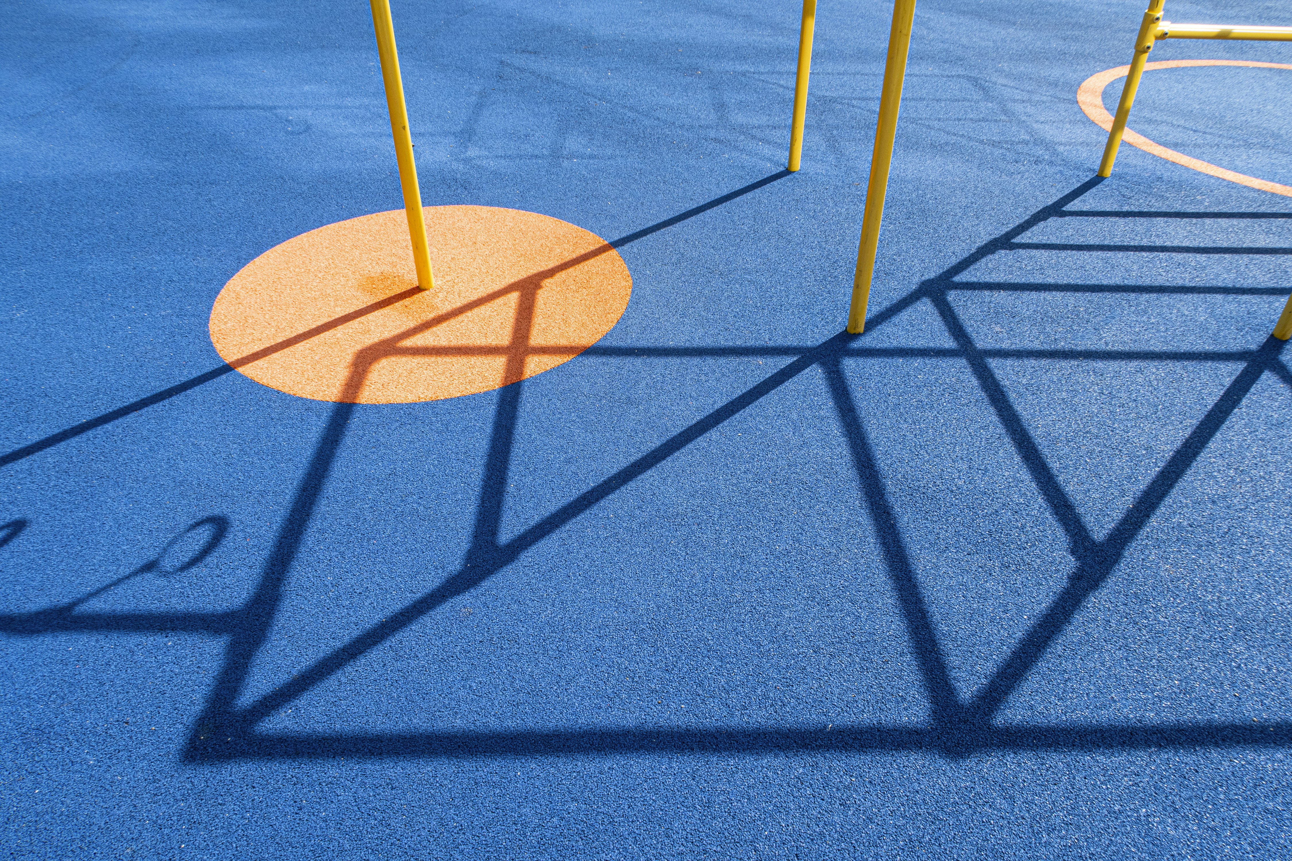 Ein Spielplatz mit blauem Boden und gelben Stangen