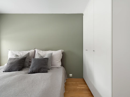 A bedroom with a white bed and green walls
