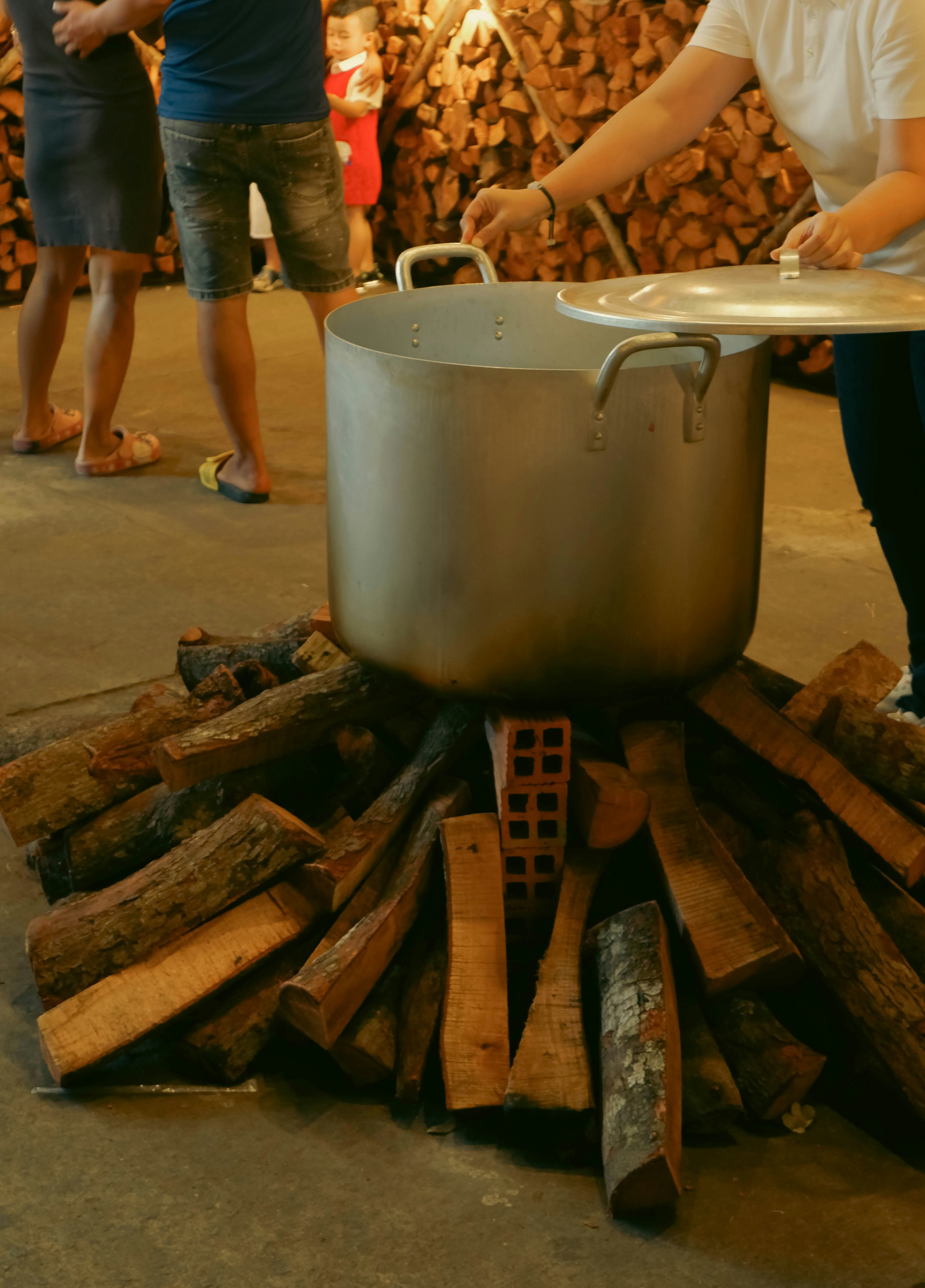 A woman cooking food over a large pot on top of a stove