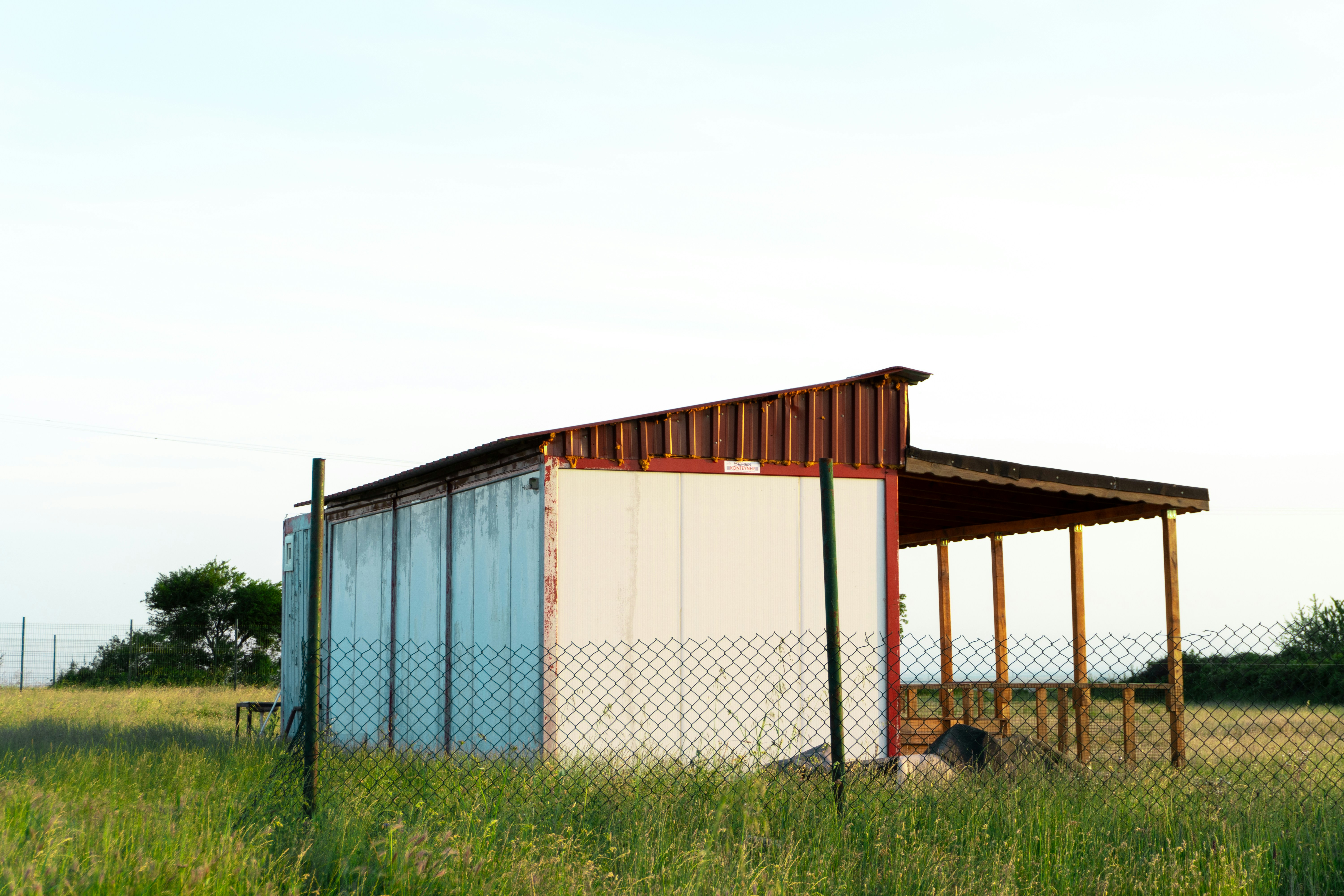 A shed in a field with a fence around it