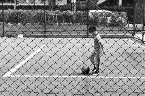 A young boy standing on a tennis court holding a ball