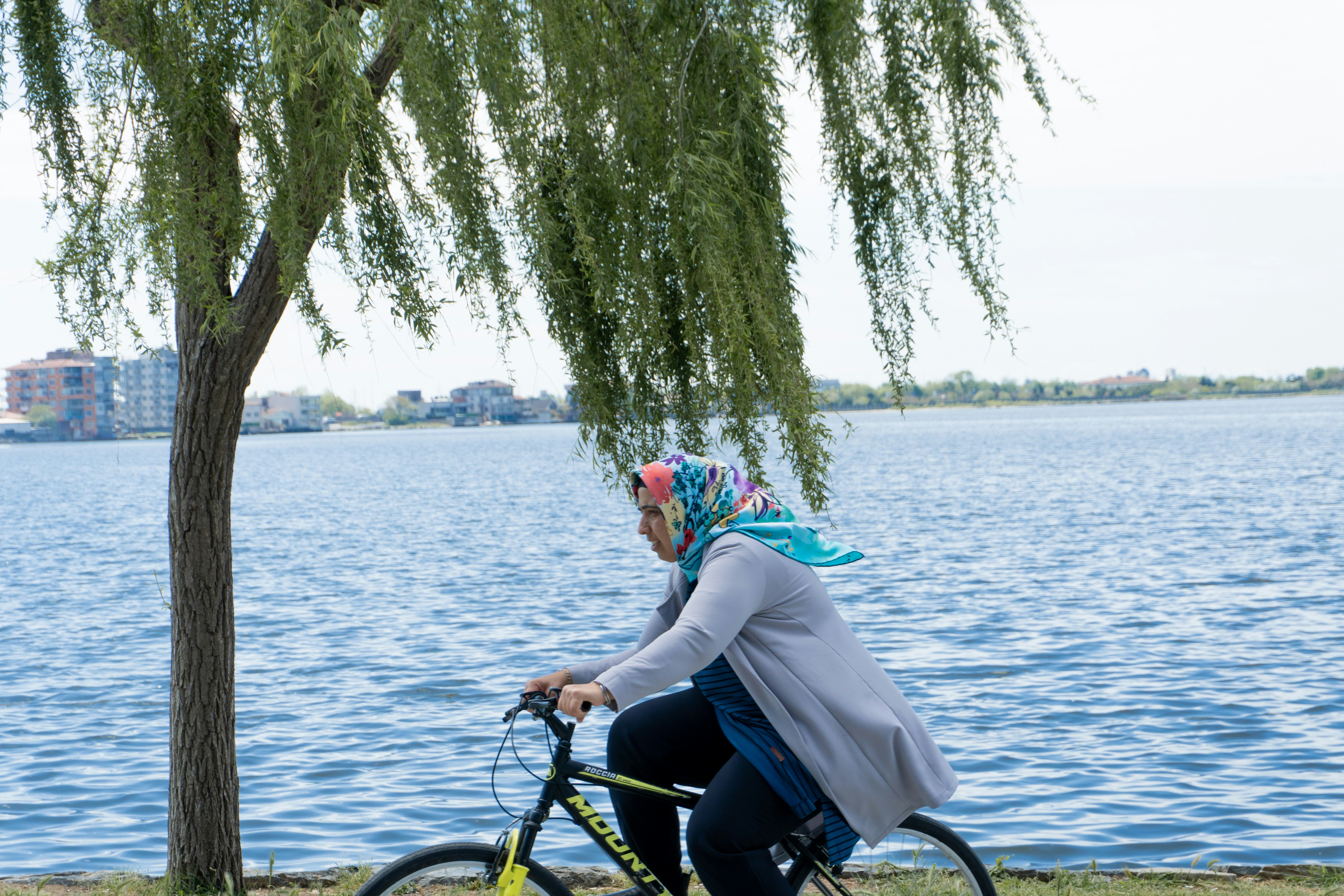 A woman riding a bike next to a tree