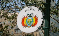 A sign on a pole with a building in the background