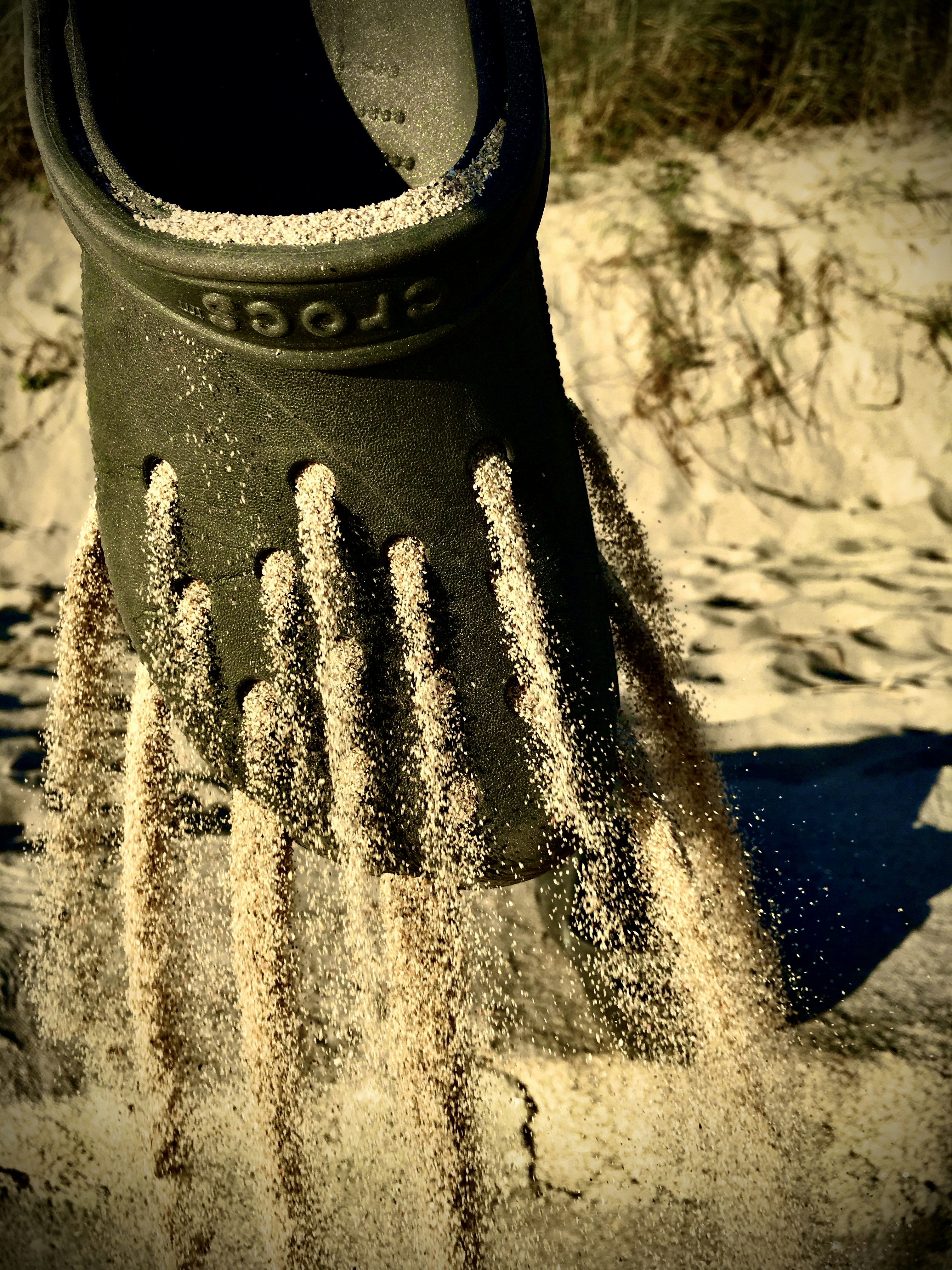 A black plastic glove is in the sand