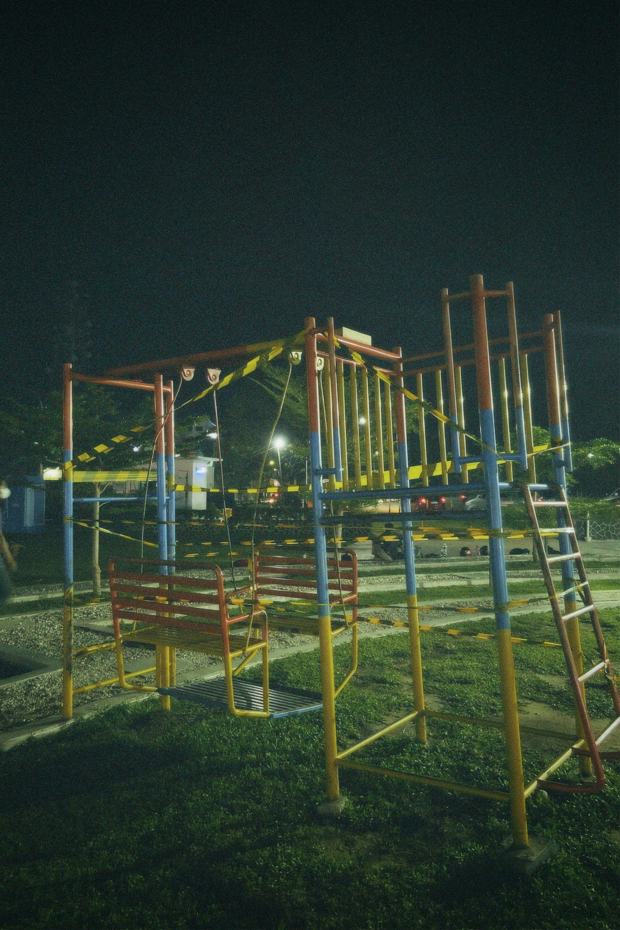 An empty playground at night with a lit up swing set