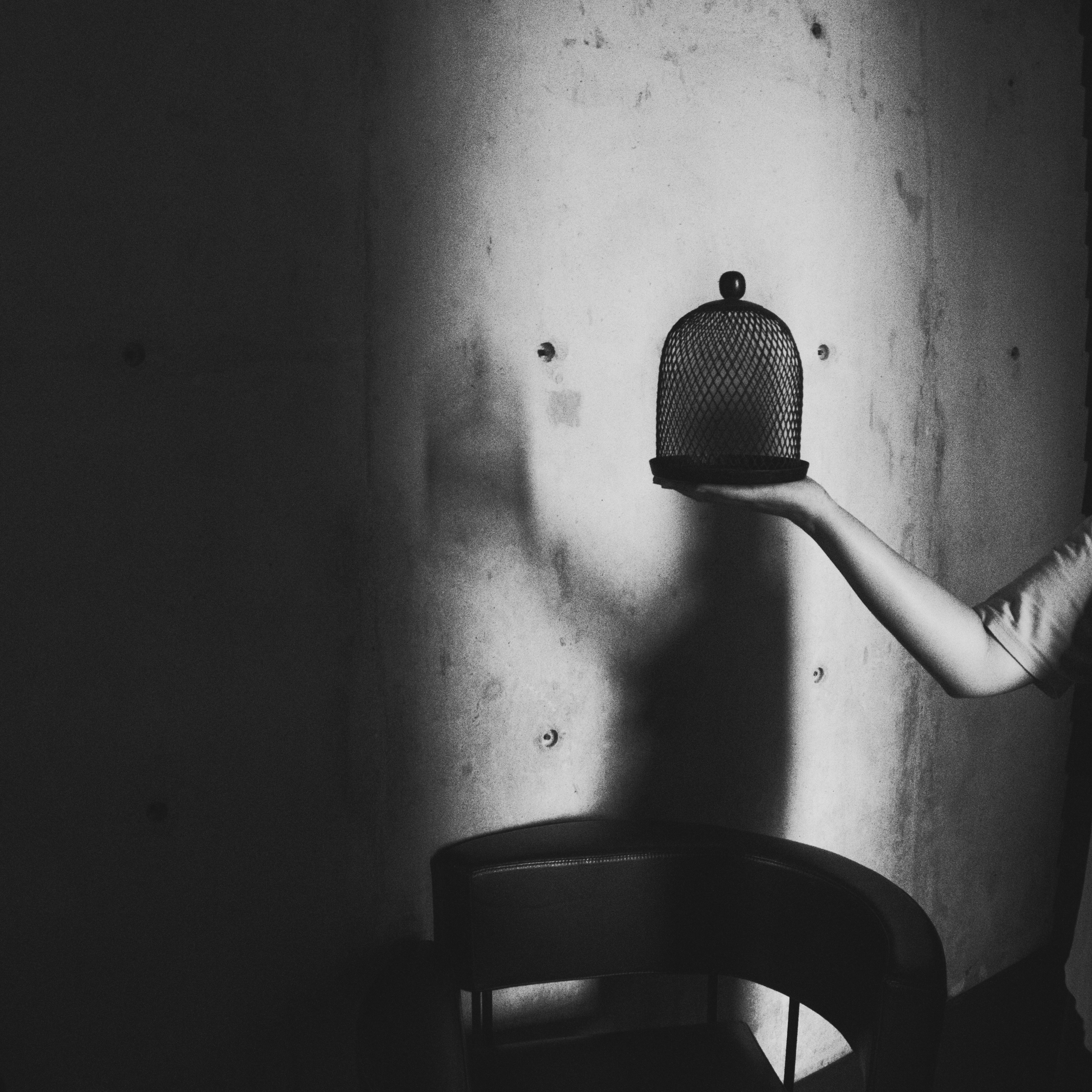 暗い部屋で鳥かごを抱く女性