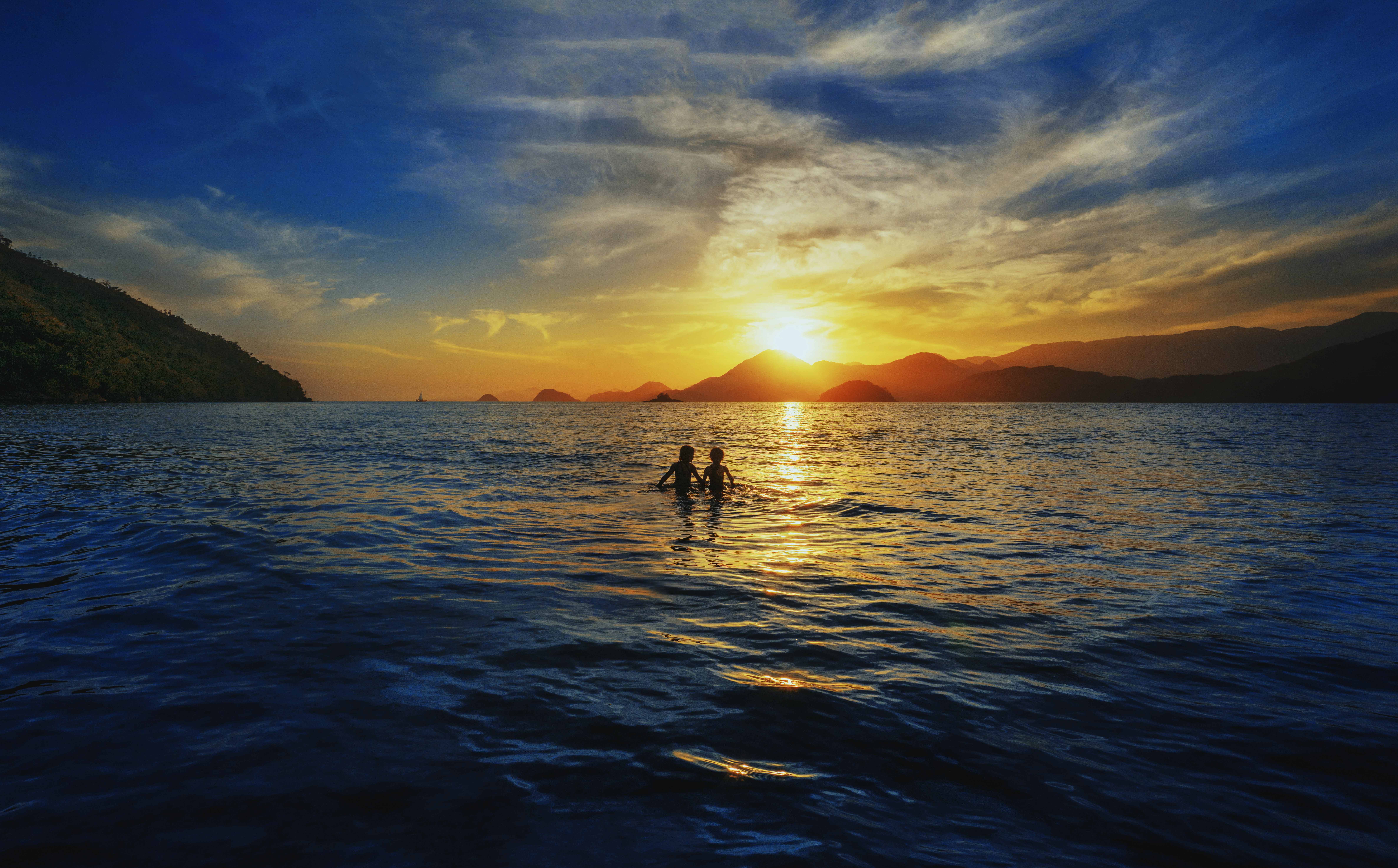 A couple of people standing on top of a body of water