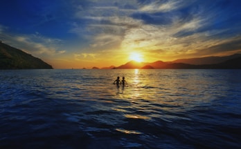 A couple of people standing on top of a body of water