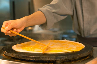 A person cooking pancakes in a pan on a stove