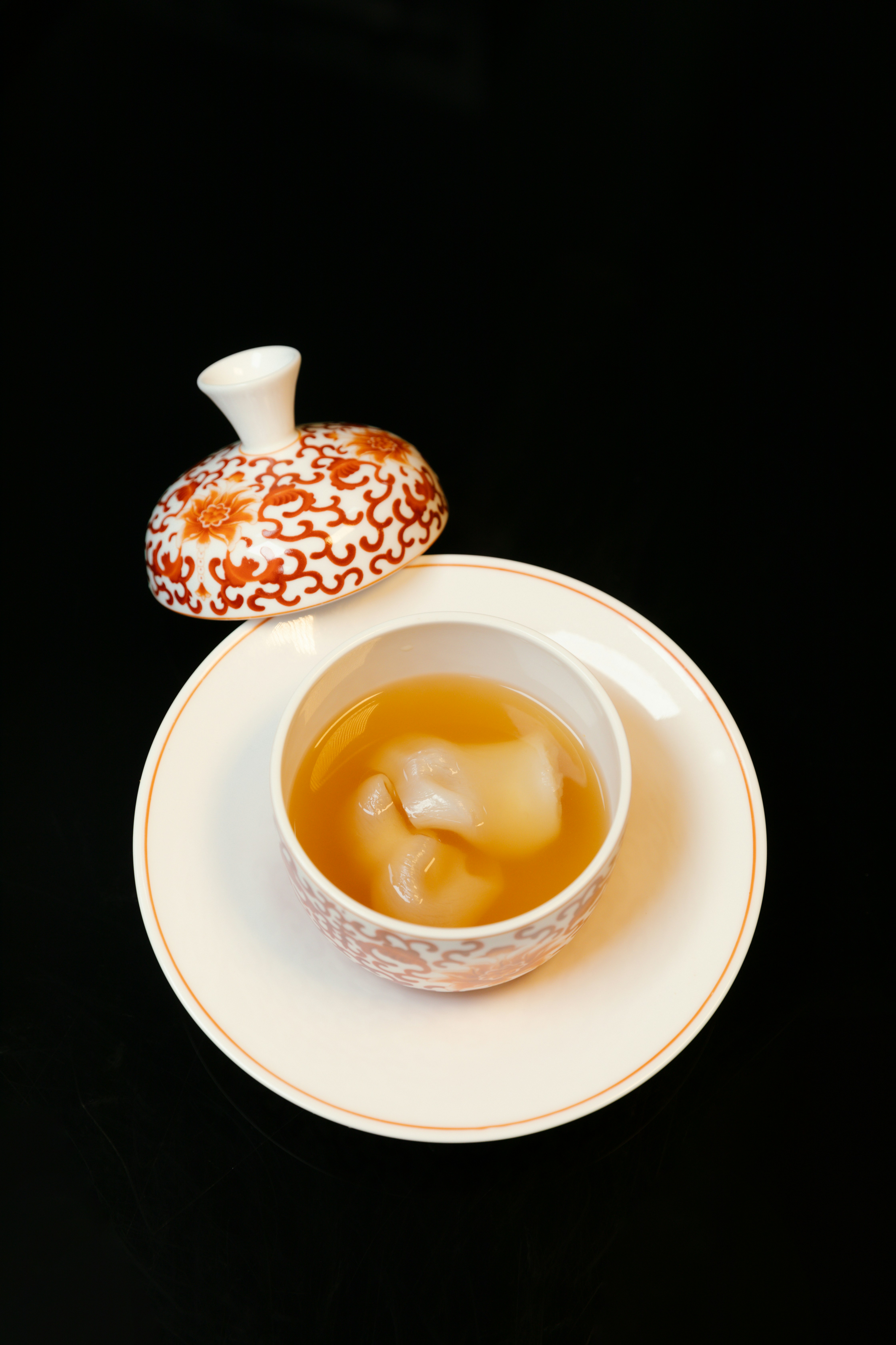 A cup of tea on a saucer next to a donut