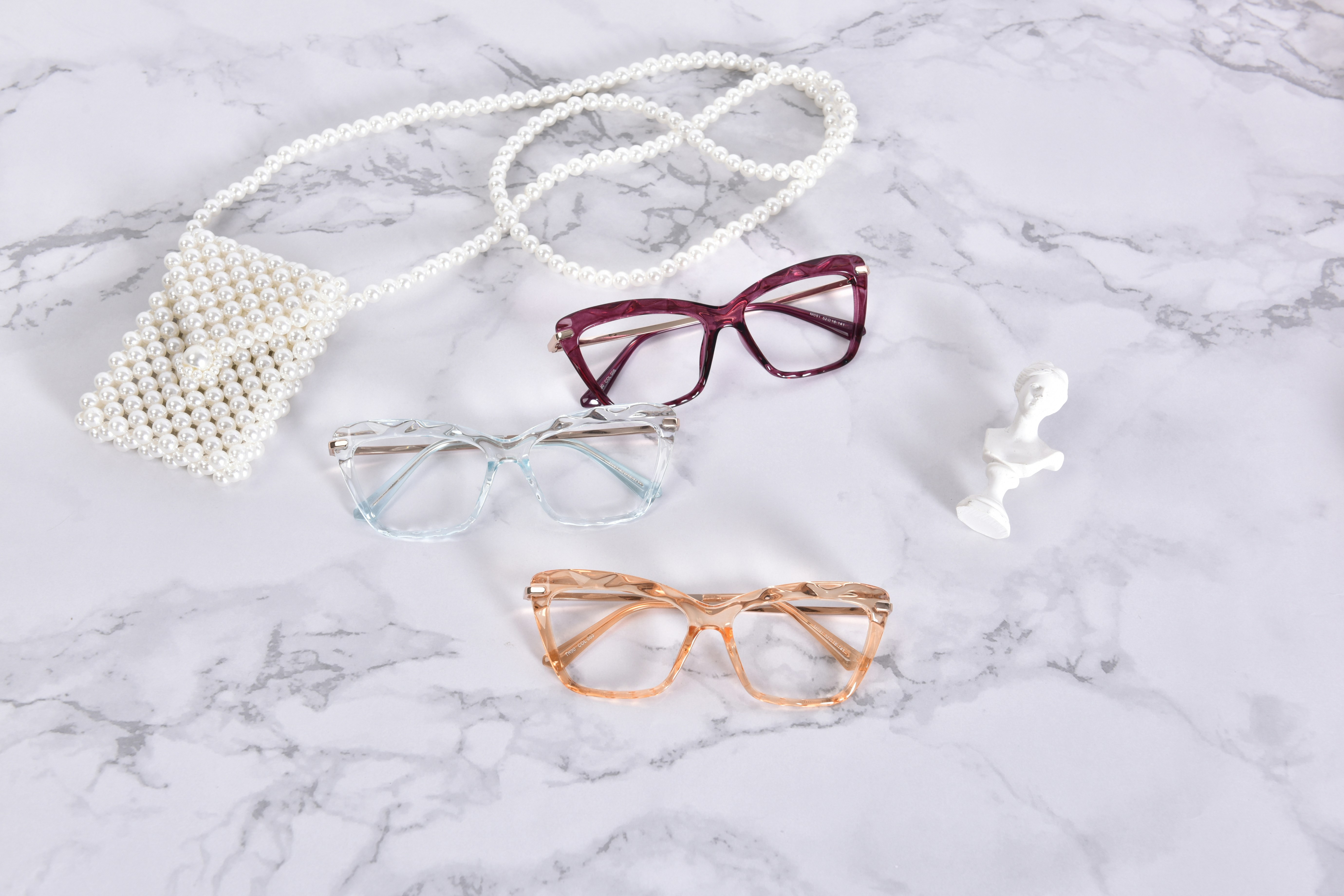 The glasses feature unique wave-patterned frames in vibrant pink, blue, and orange hues. Set against a sleek marble background, they create a stunning contrast, drawing attention to their intricate design and color palette.