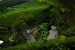 A car driving down a road surrounded by lush green hills