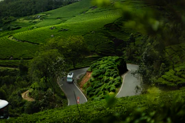 A car driving down a road surrounded by lush green hills