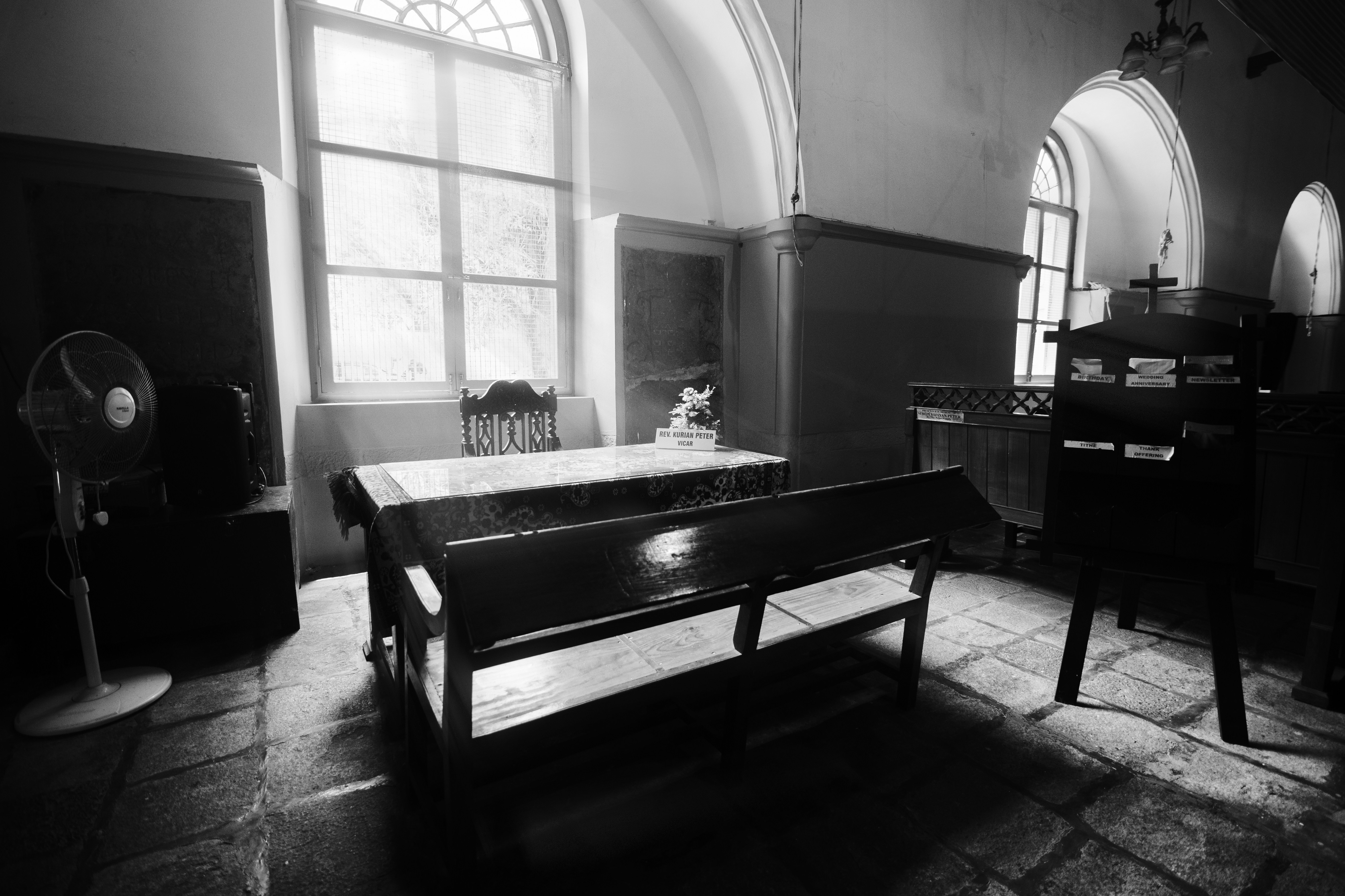 A black and white photo of a bench in a church