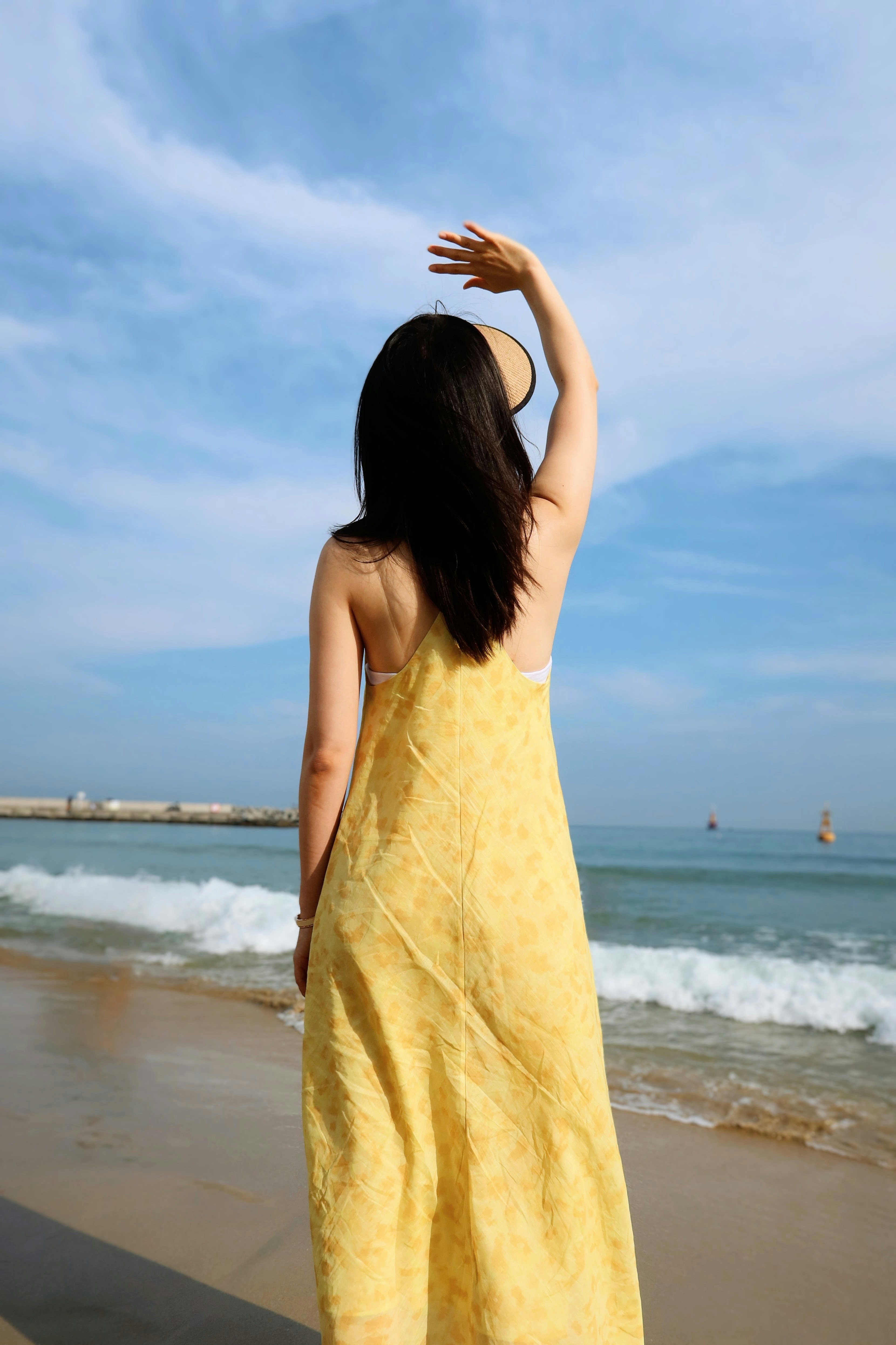 A woman in a yellow dress standing on a beach