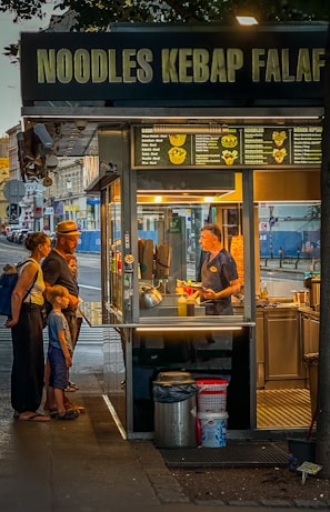 A group of people standing outside of a kiosk