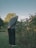 A man standing in the grass next to a bush