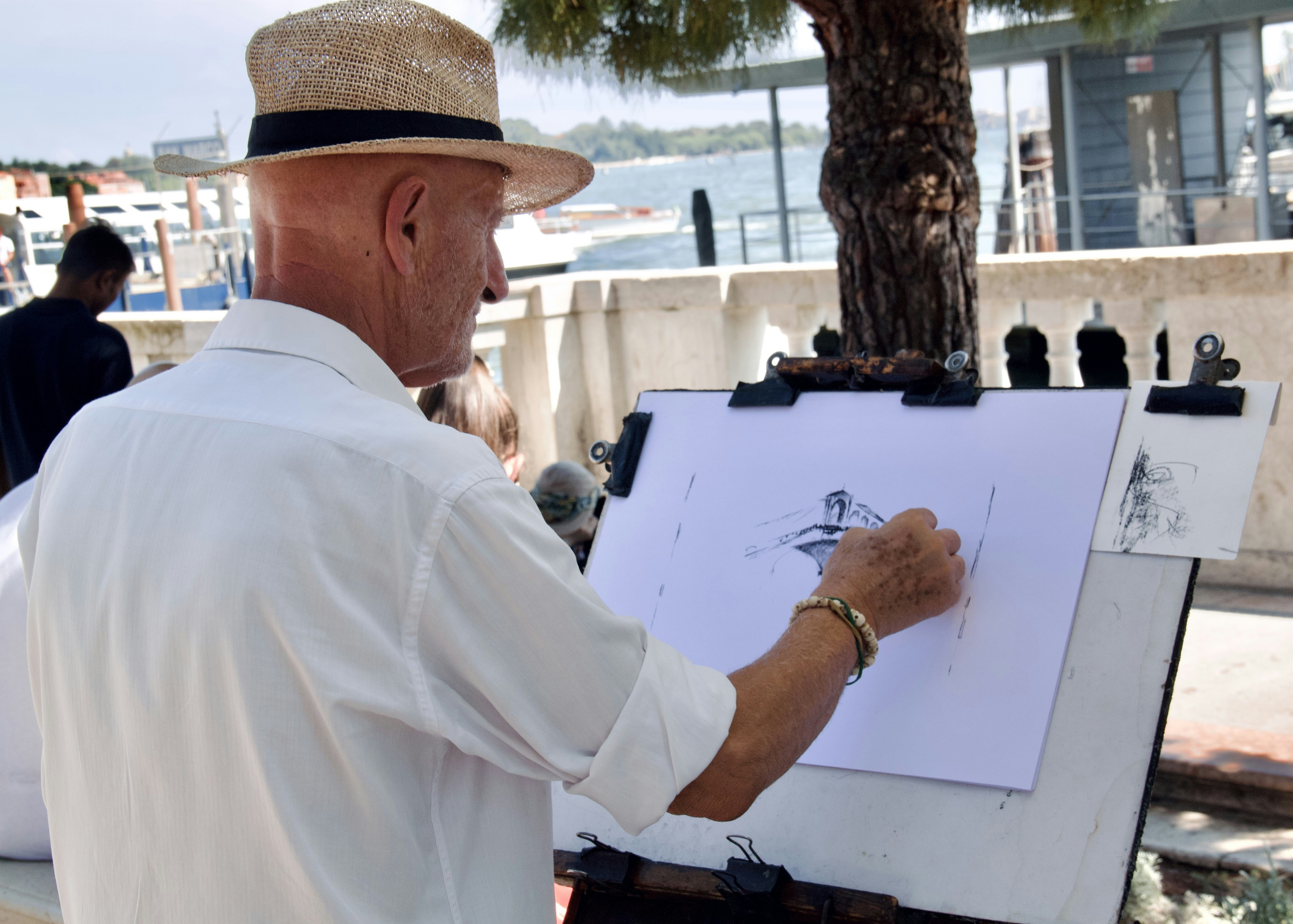 A man in a hat is drawing on a canvas