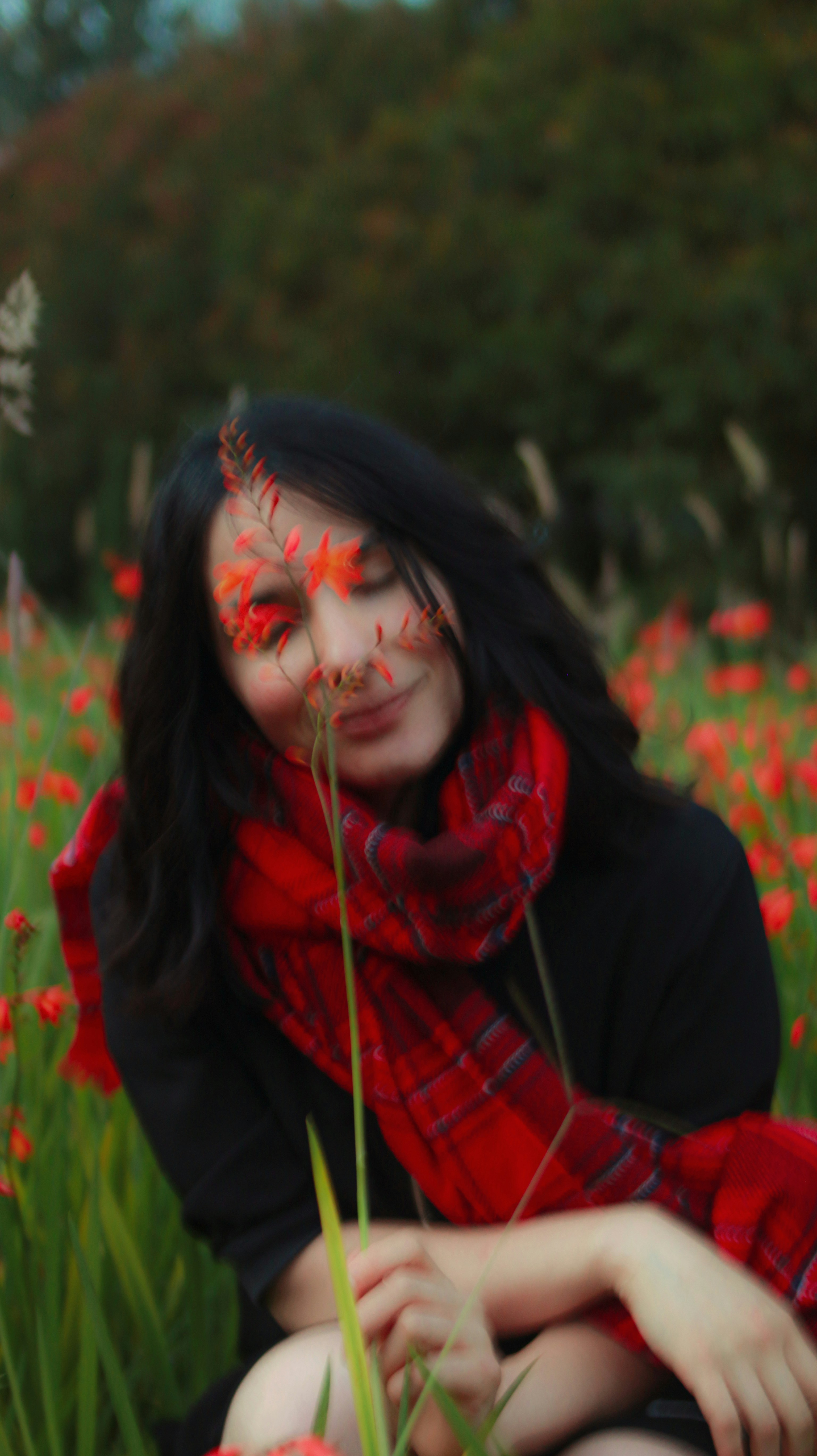 A woman sitting in a field of red flowers