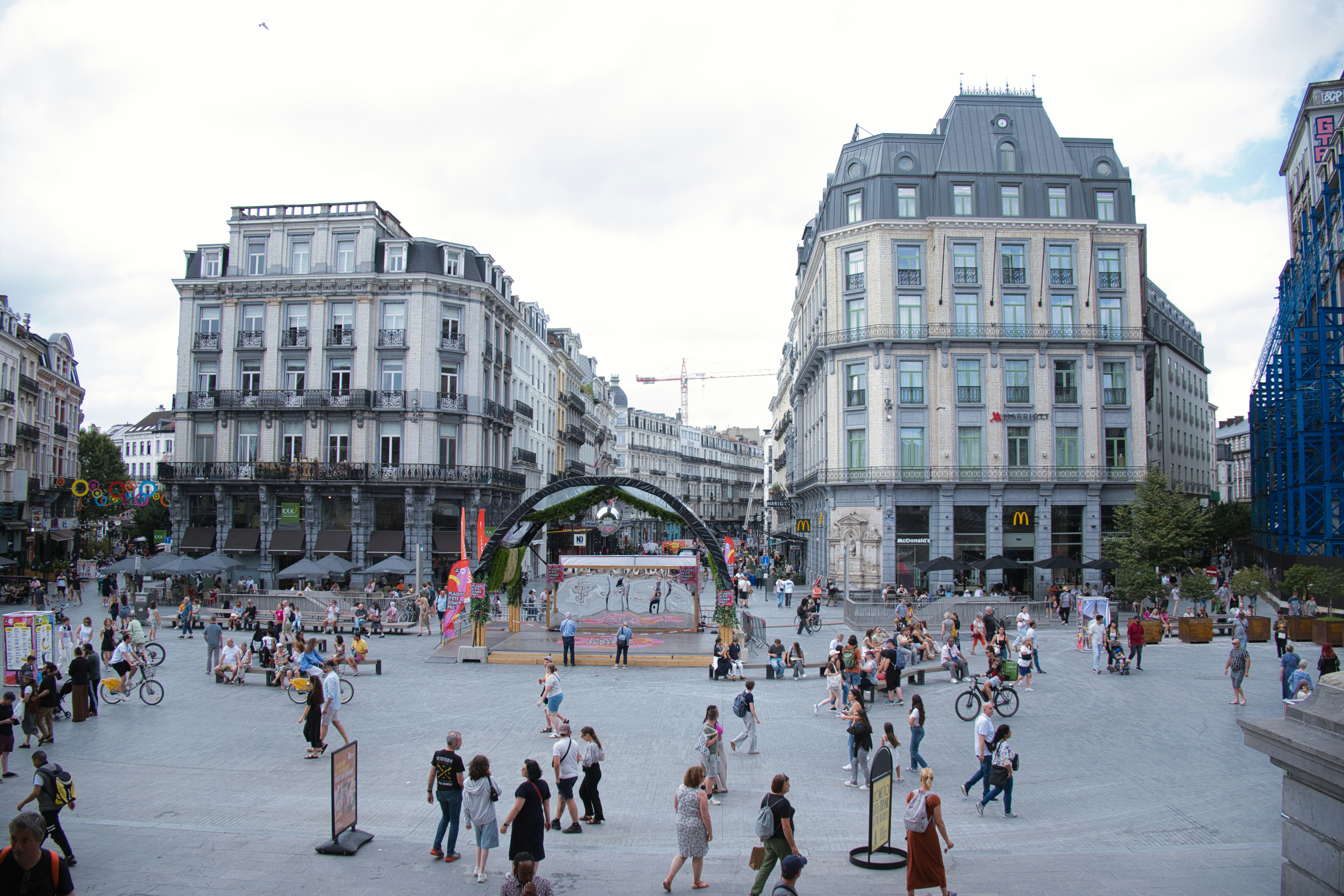A crowd of people walking around a city square