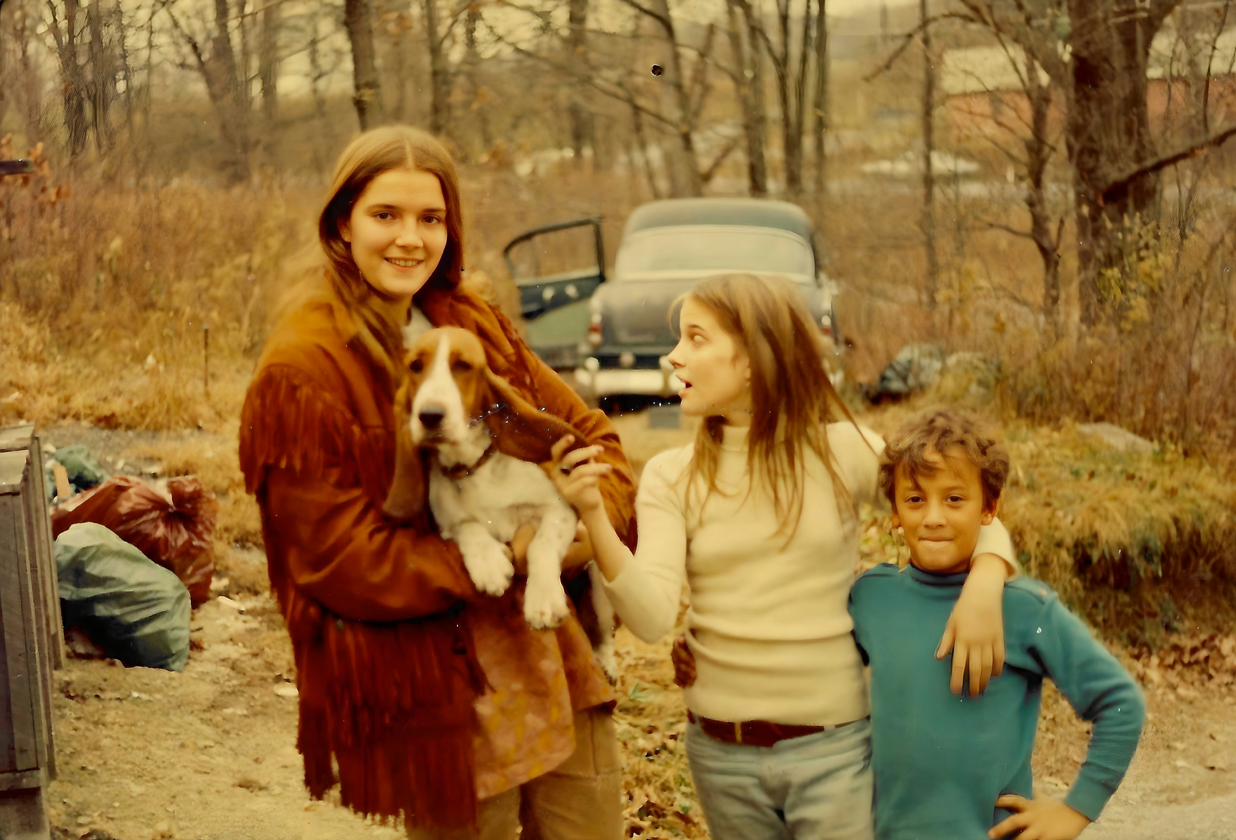 A woman holding a dog standing next to two children