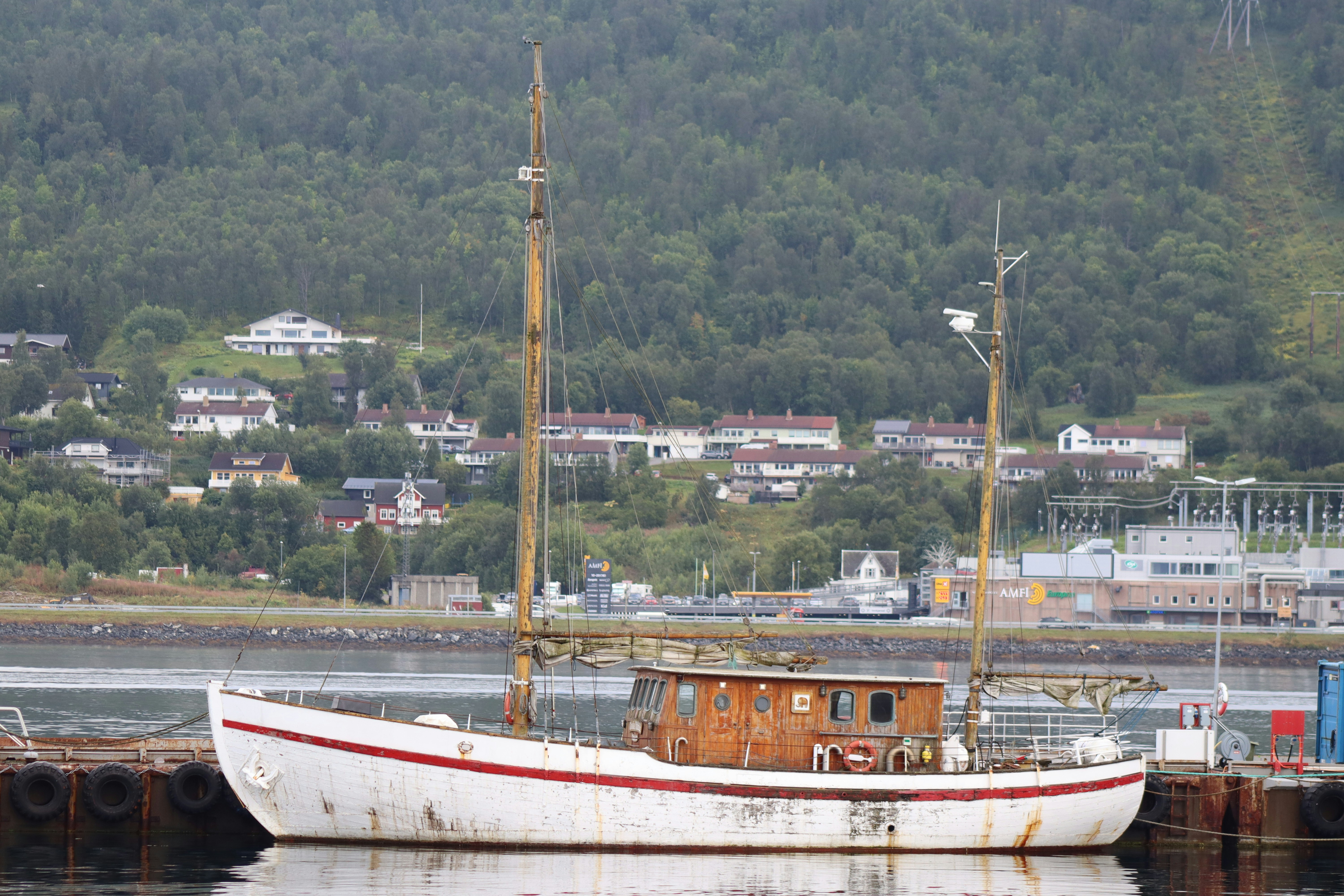 Ein weißes Boot sitzt im Wasser neben einem Dock