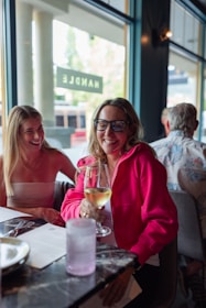 Two women sitting at a table with a glass of wine