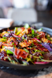 A plate of bacon salad with red onions and green peppers