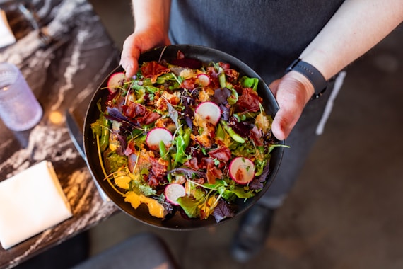 A person holding a bowl of food on a table