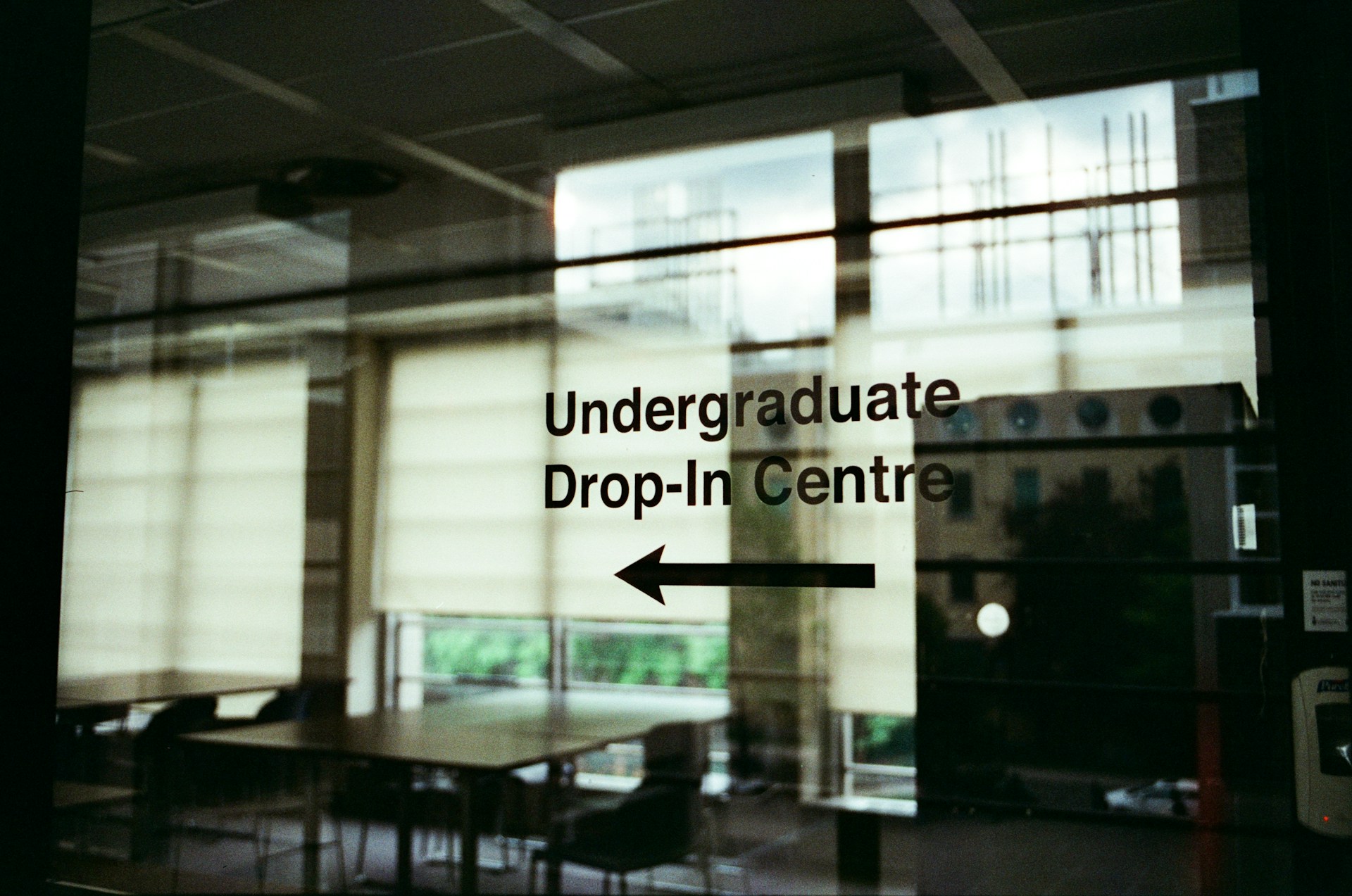 A large window with a sign that says under graduate drop - in centre