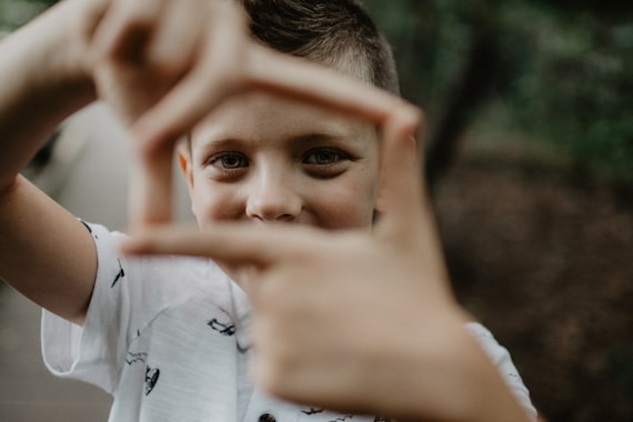 A young boy making a heart with his hands