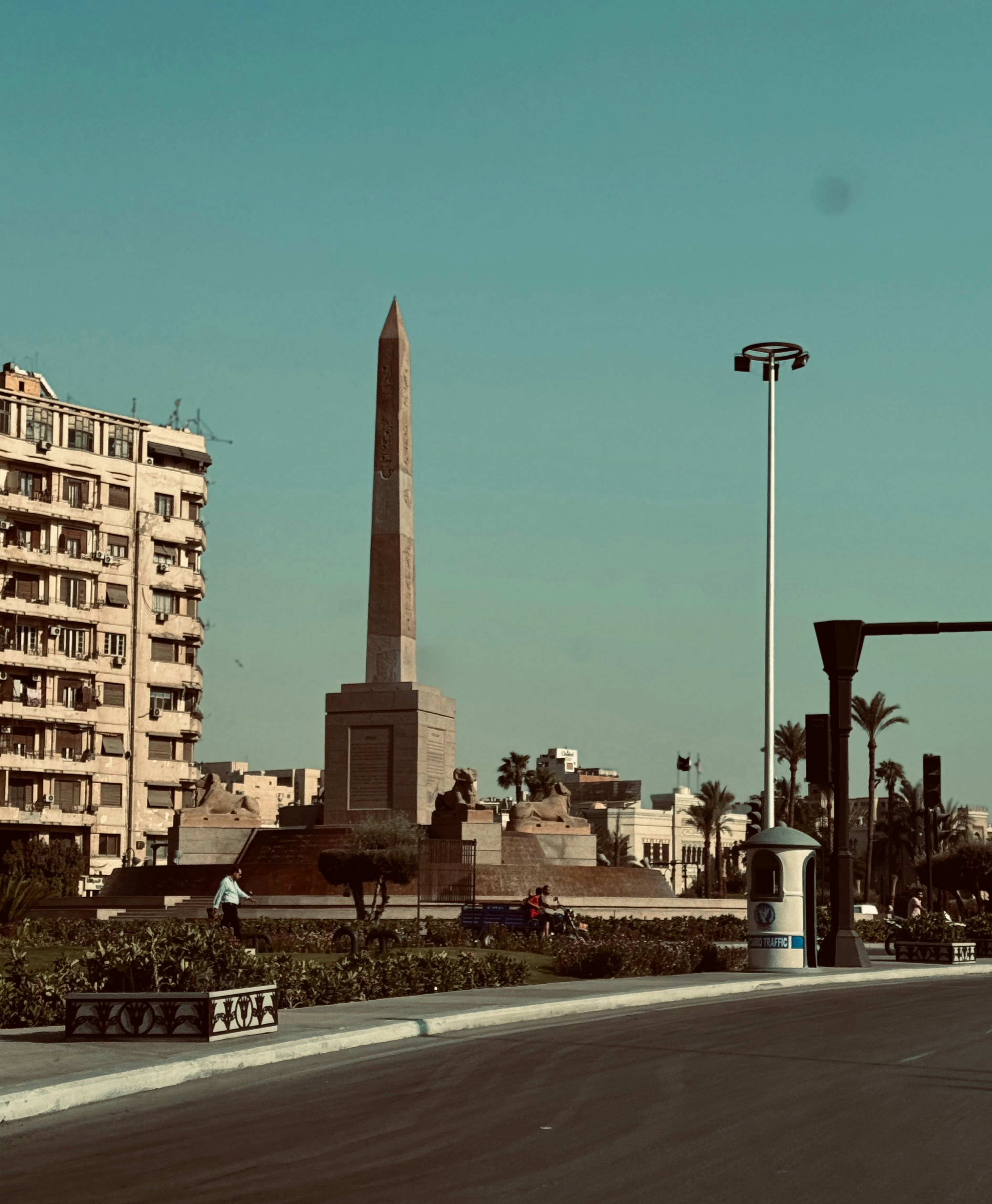 A view of a street with a tall obelisk in the background