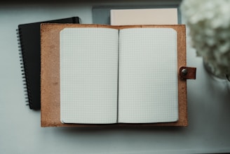 An open notebook sitting on top of a desk next to a flower