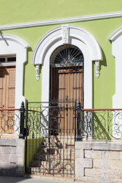 A green building with a wrought iron gate