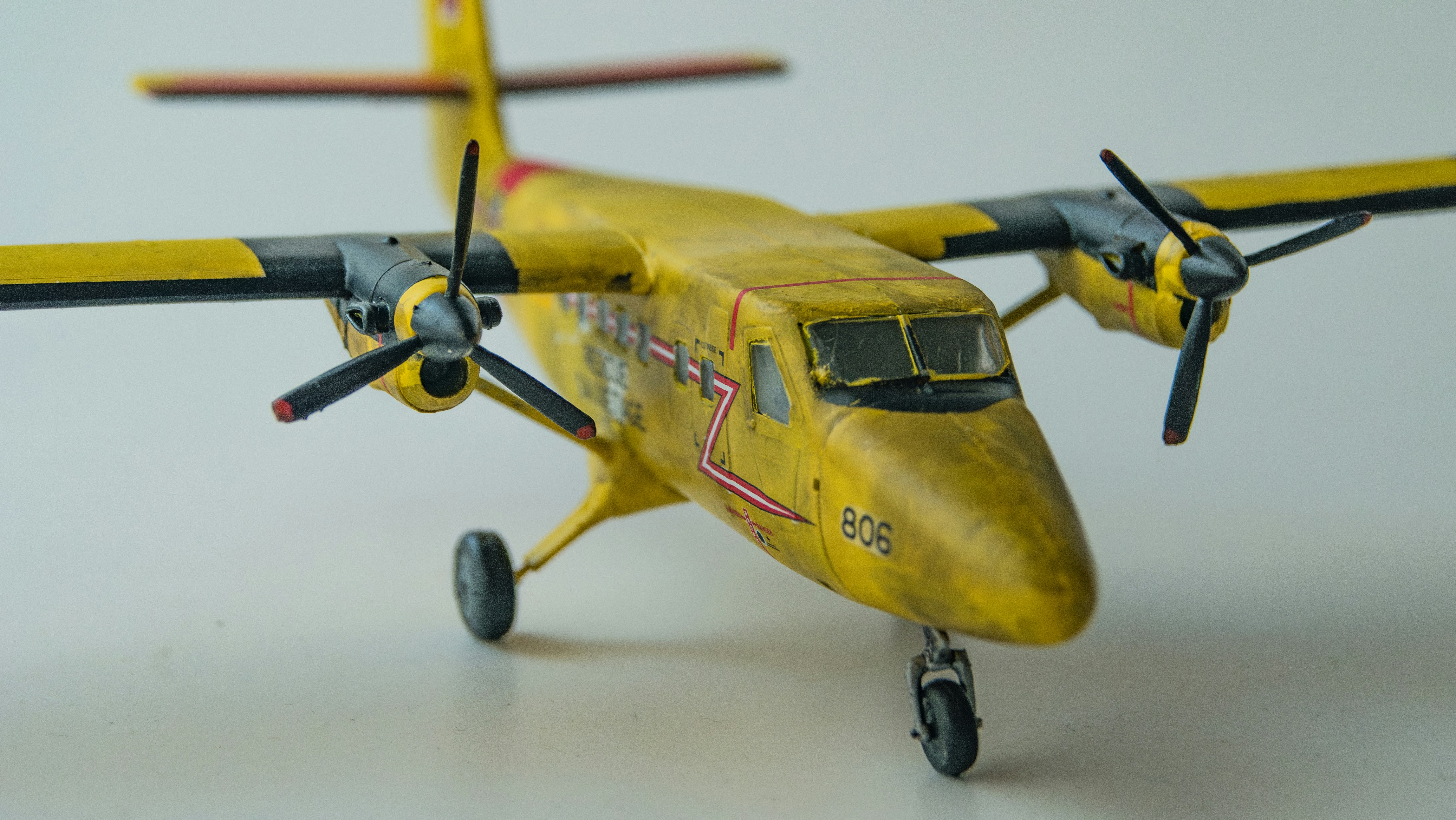 A small yellow airplane with propellers on a white surface, 