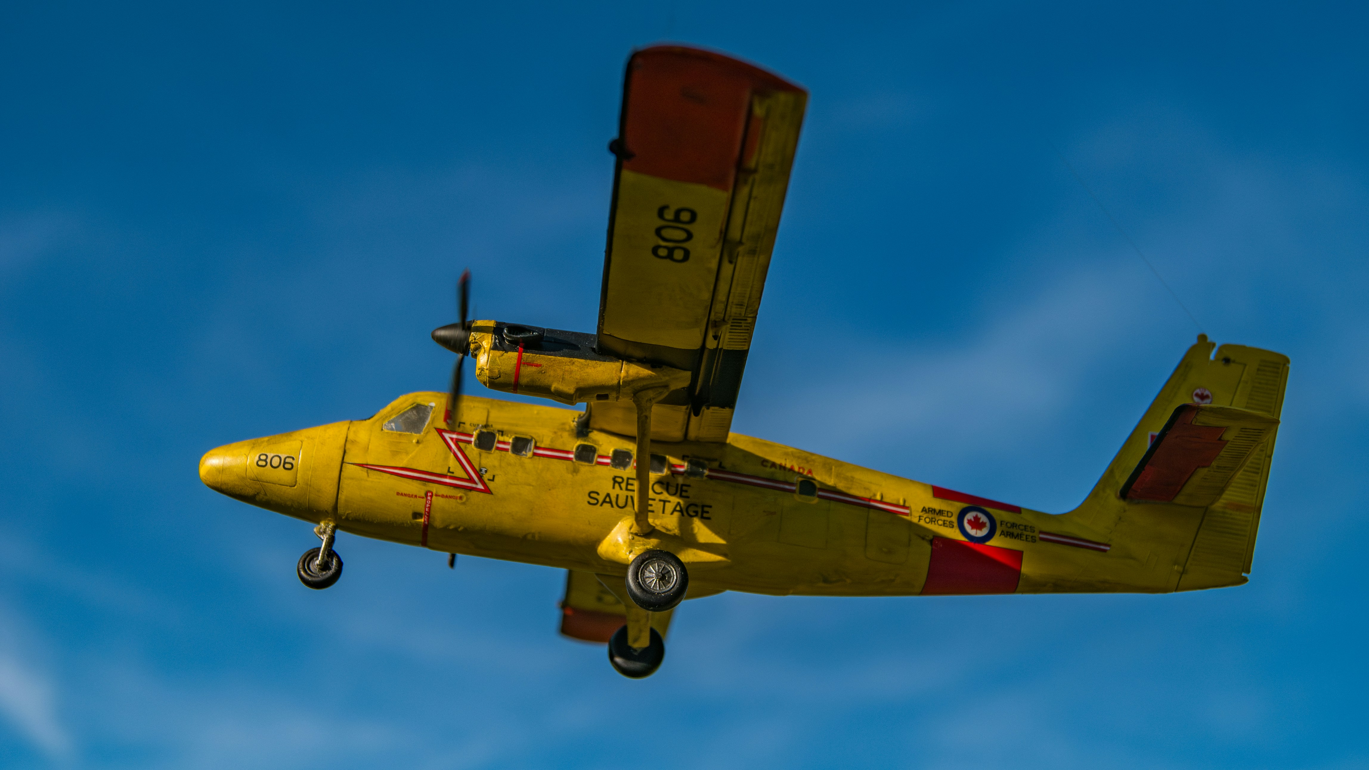 A small yellow airplane flying through a blue sky, 