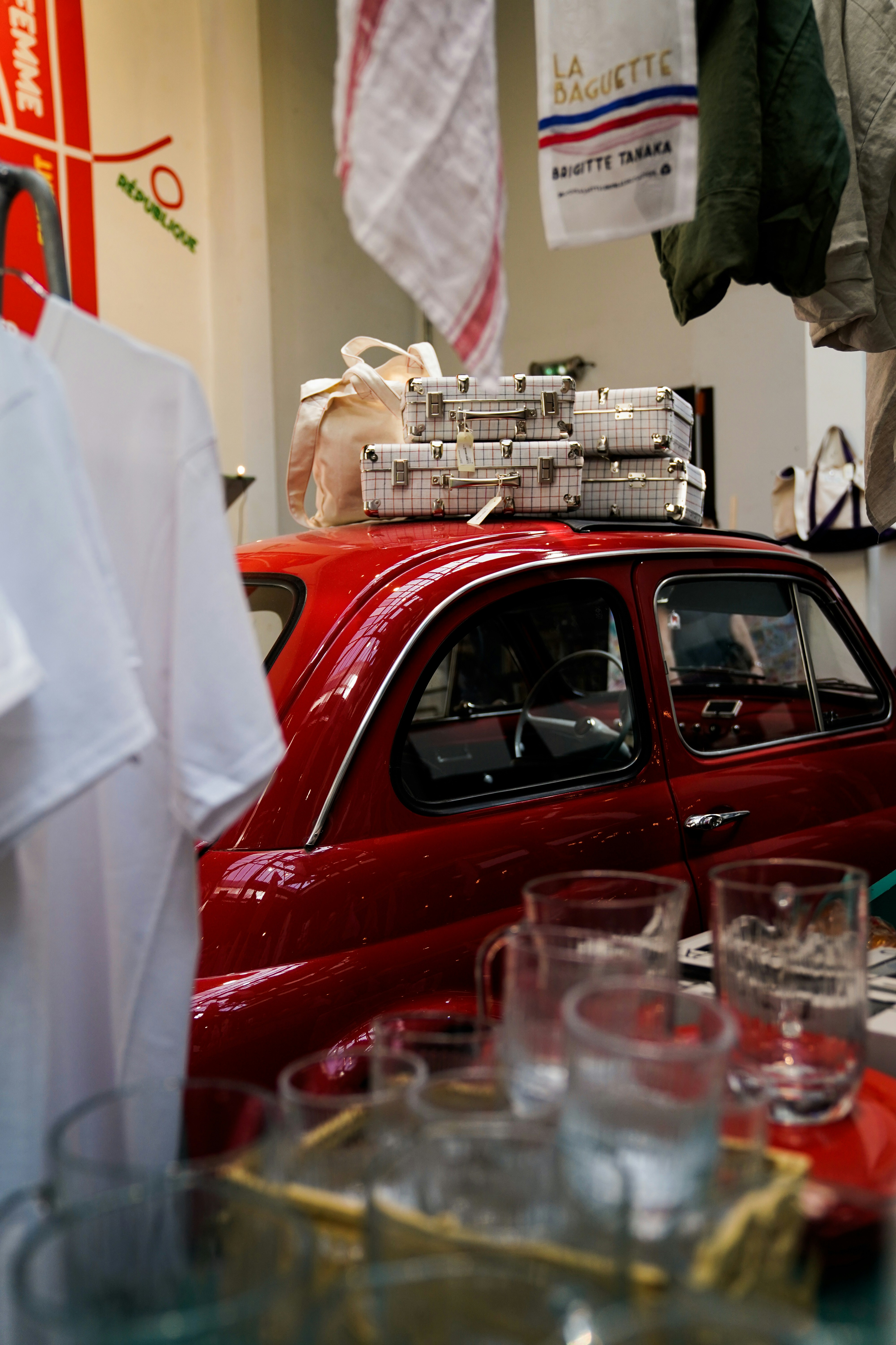 A red car parked next to a pile of glasses