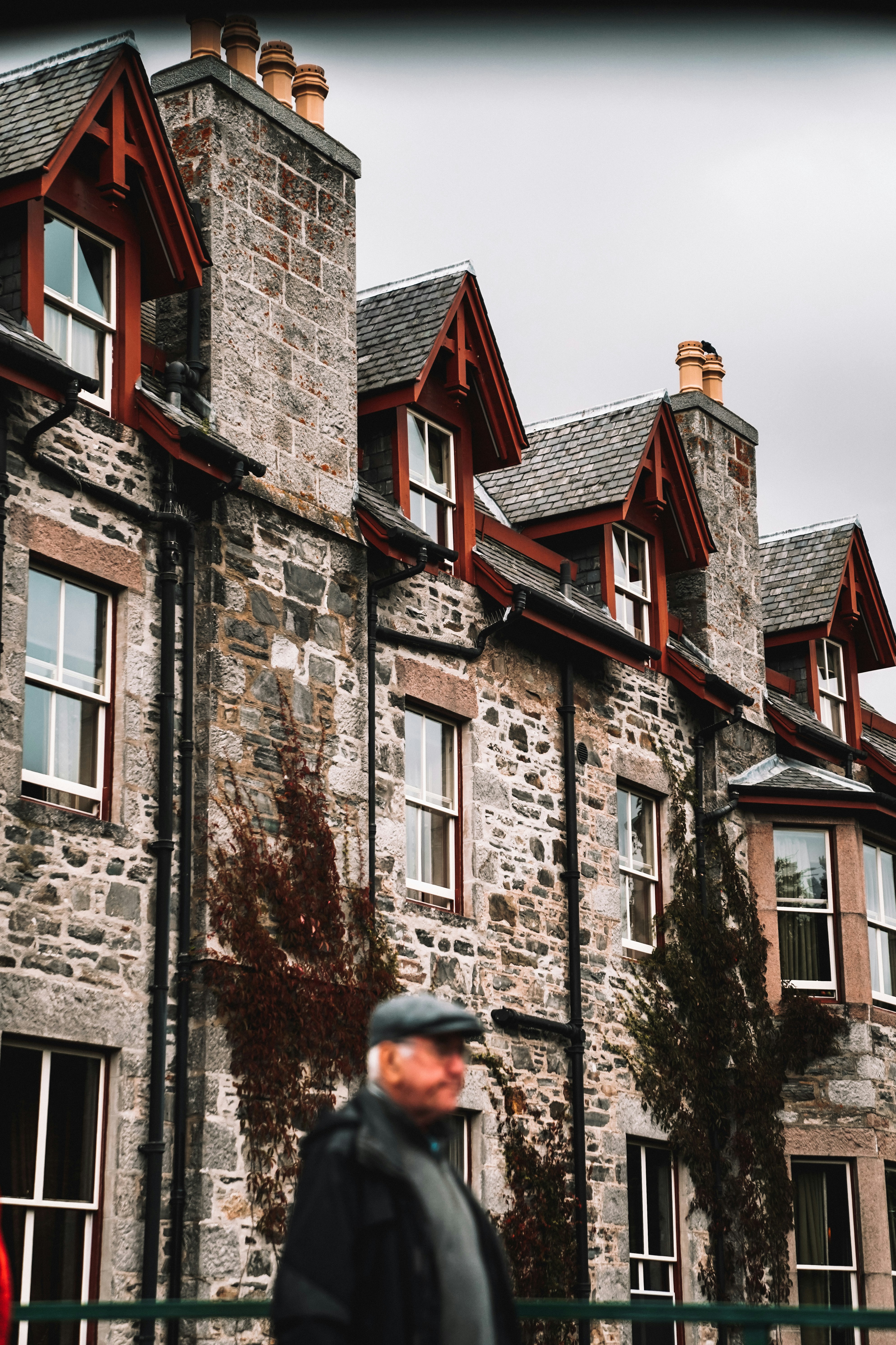 A man walking past a tall stone building