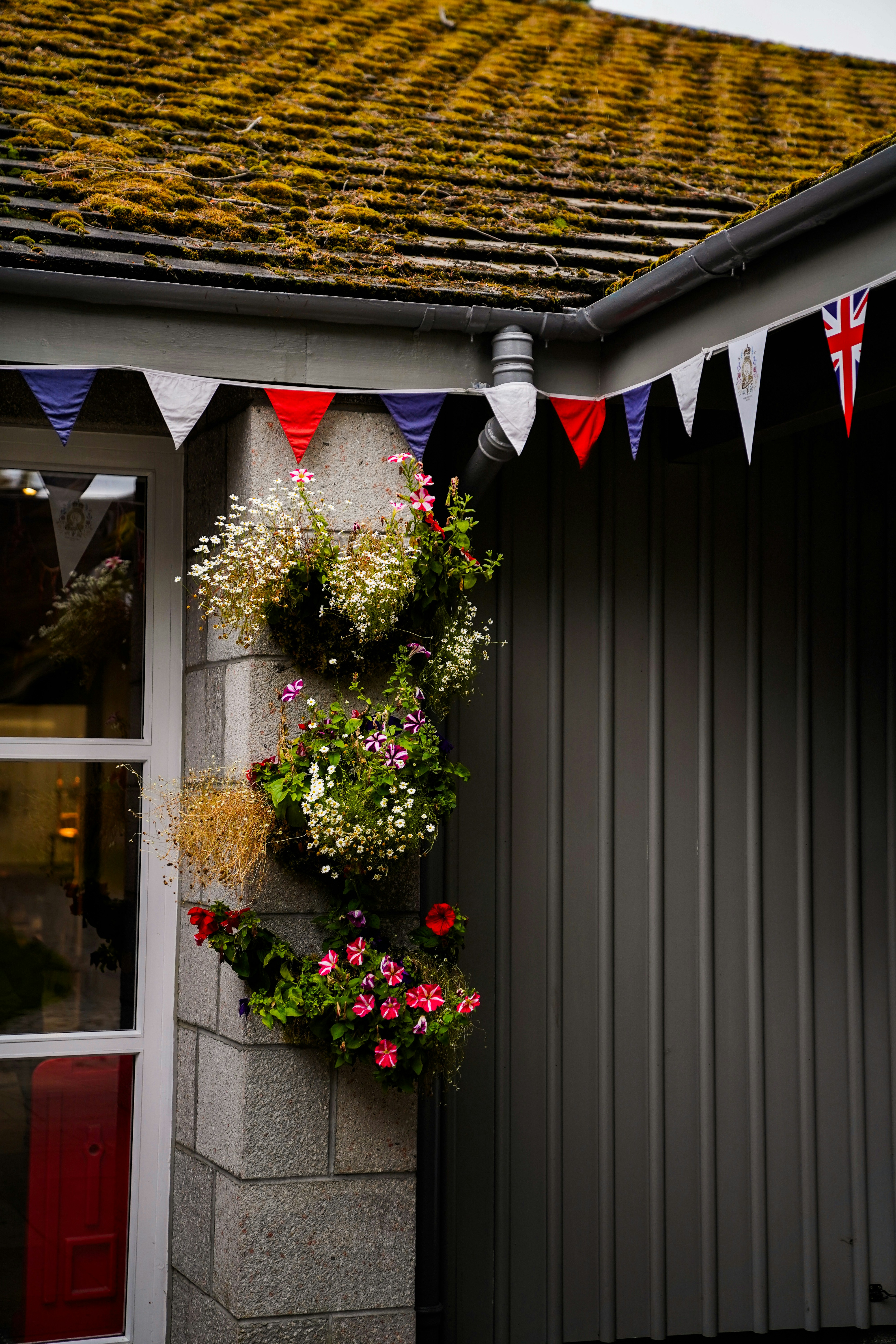 A building with a flag and flowers hanging from it's side
