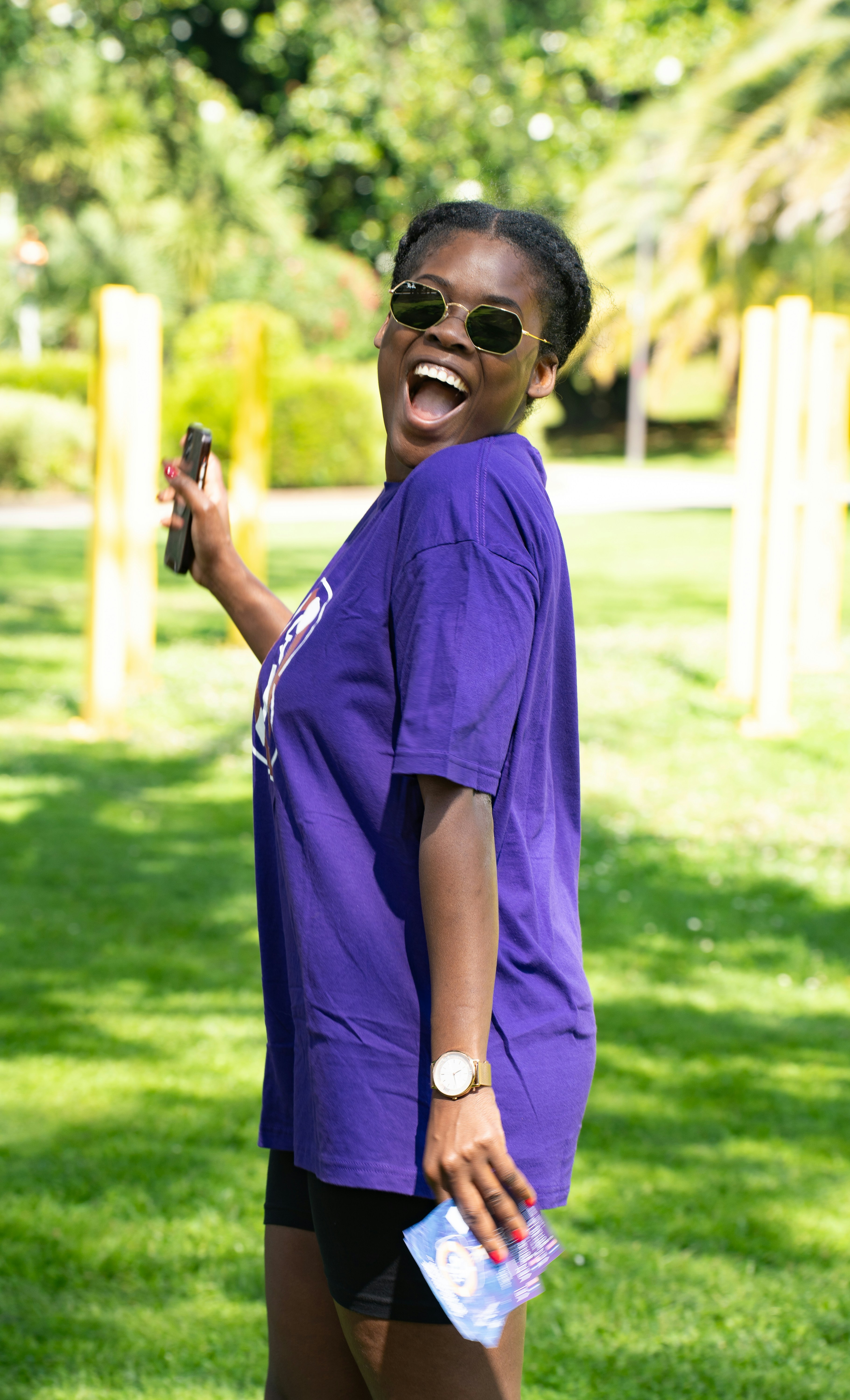 A woman in a purple shirt laughing and holding a cell phone