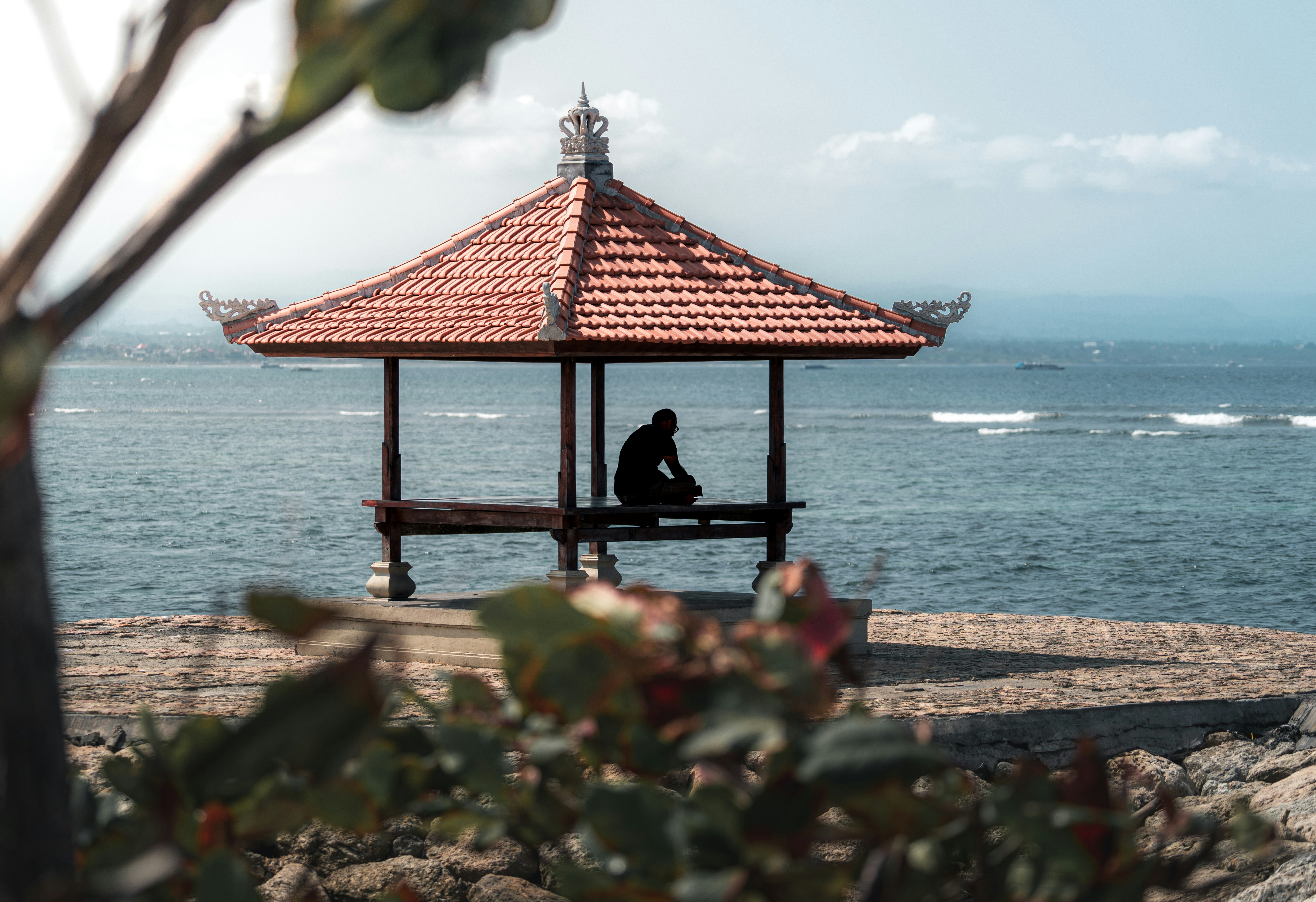 A man sitting on a bench in front of the ocean