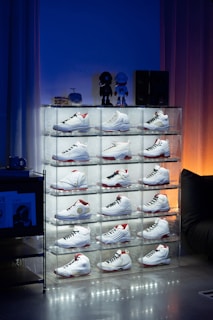 A stack of white sneakers sitting on top of a glass shelf
