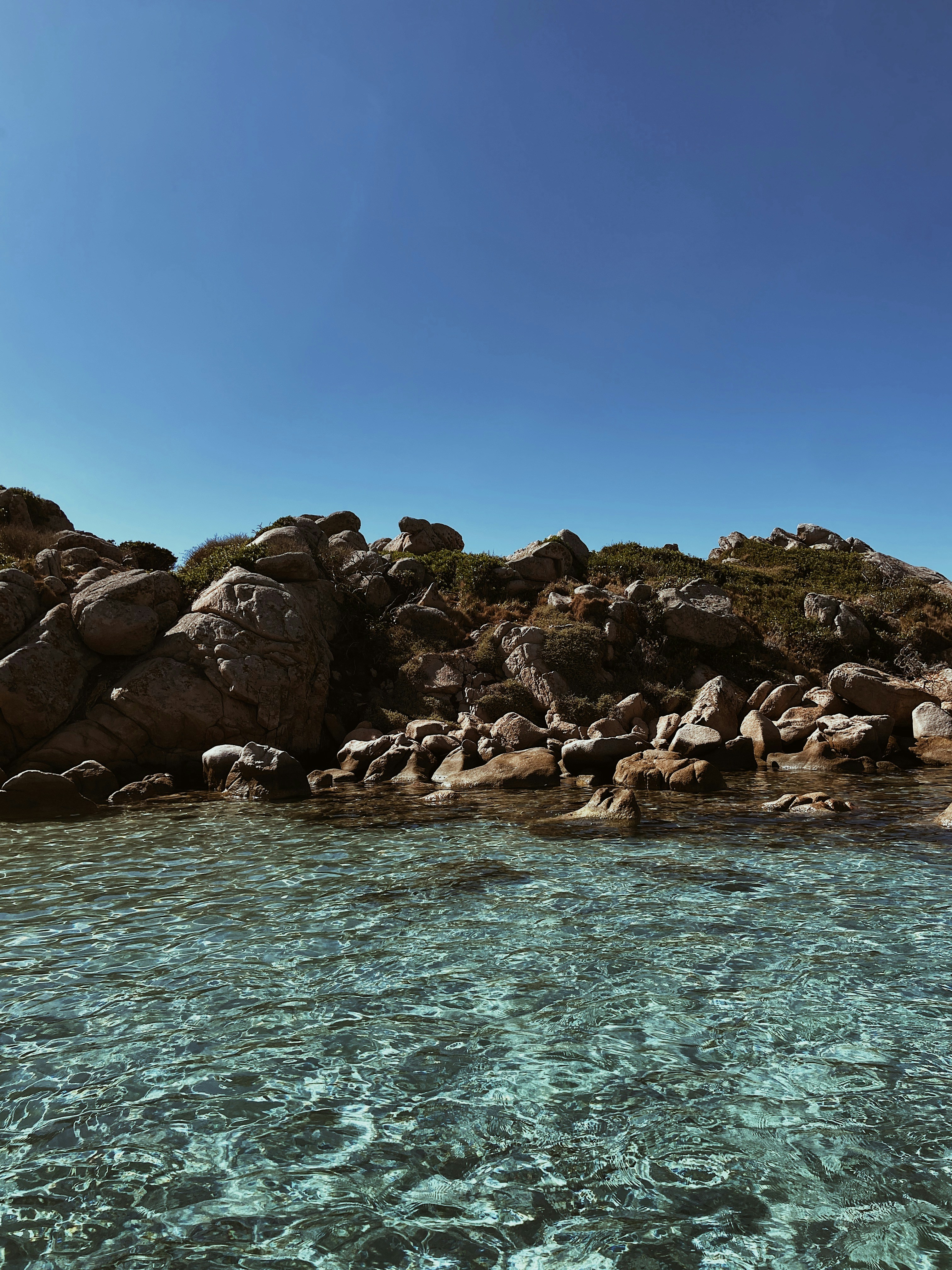 A body of water with rocks in the background photo Free Italy Image