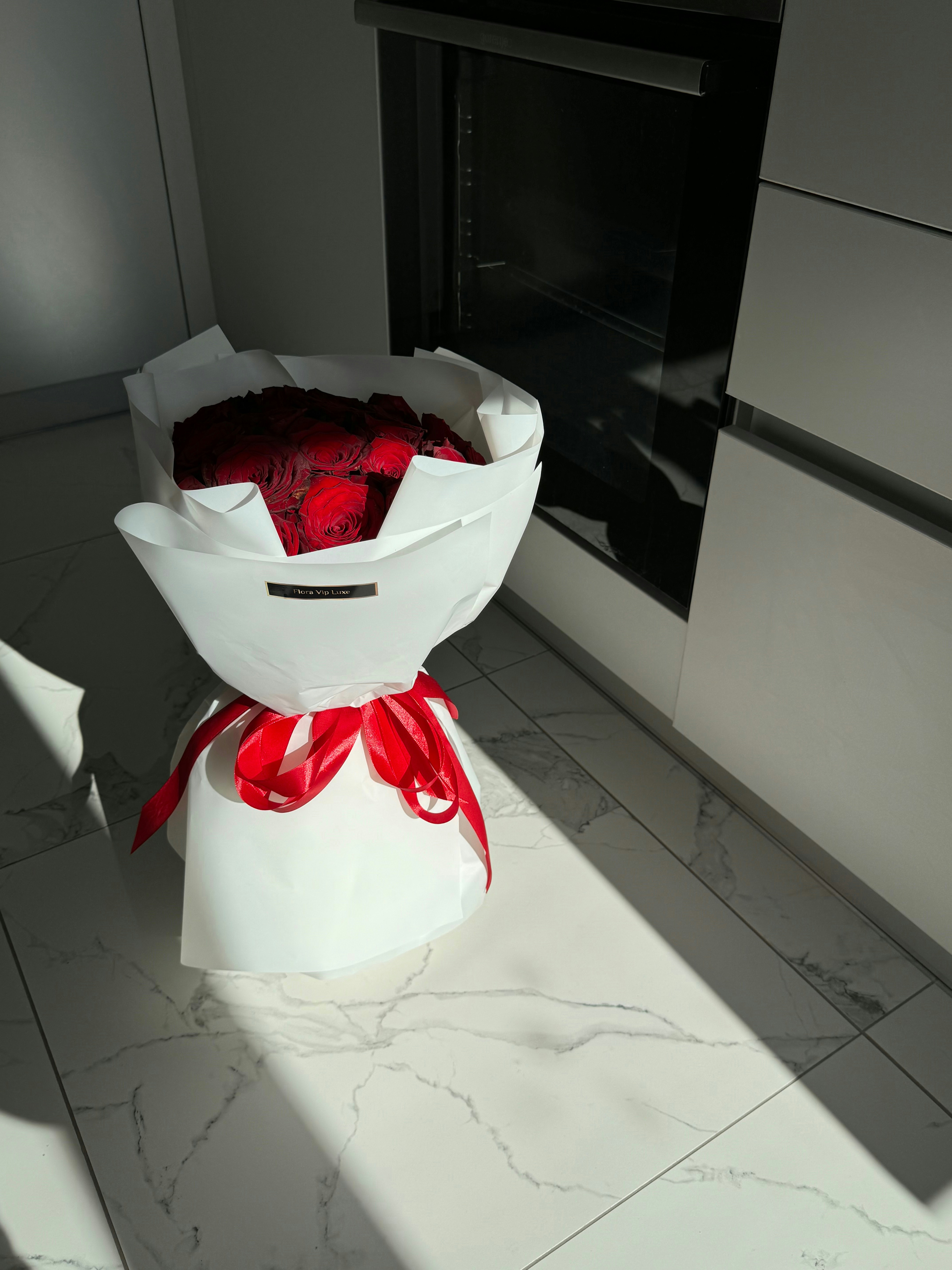 Lush pink and red rose bouquet wrapped in elegant kraft paper on marble surface